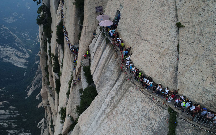 Tourists walk on plank road built on cliff at Huashan Mountain