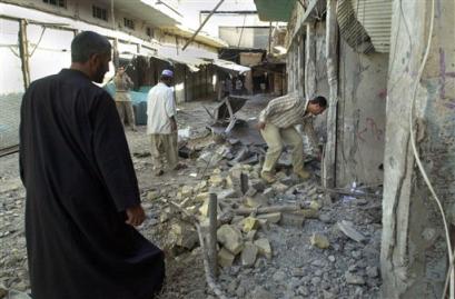 Iraqis walk among buildings damaged by an air strike in Fallujah, Iraq, Sunday, Nov. 7, 2004. The Iraqi government Sunday declared a state of emergency for 60 days throughout the country except for Kurdish-run areas of the north as U.S. and Iraqi forces prepare for an expected all-out assault on rebels in Fallujah. [AP]