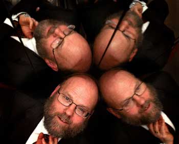 Professor Ian Wilmut is reflected in a mirror as he poses for photographs after a news conference in Edinburgh, February 8, 2005. Wilmut who created Dolly the sheep, the world's first cloned mammal, was granted a licence on Tuesday to clone human embryos for medical research. Wilmut, of the Roslin Institute in Edinburgh, plans to obtain stem cells for research into Motor Neurone Disease (MND), a procedure that divides the medical world along ethical lines.