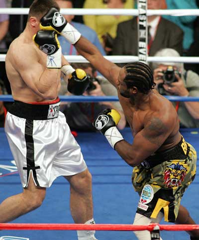 World Boxing Organization champion Lamon Brewster (L) celebrates as referee Gino Rodriguez (C) ends the bout against Andrew Golota during the first round of their World Boxing Organization heavyweight title fight in Chicago May 21, 2005. Brewster won by technical knock-out 53 seconds into the first round. [Reuters]