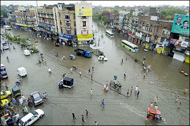 Pakistani people and vehicles wade through flooded streets in Lahore, 01 July 2005. Pakistan warned people living in seven districts along the banks of the Chenab river in the east of the country to leave their homes and move to safer locations due to an imminent flood threat(AFP/File