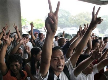 Supporters of Philippine President Gloria Macapagal Arroyo flash signs outside the session hall during impeachment hearings at Congress in suburban Quezon City, north of Manila, Wednesday, Aug. 31, 2005.