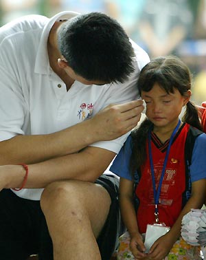 Chinese basketball star and Houston Rockets center Yao Ming (L) wipes tears for a Chinese AIDS orphan Zhang Yun during an HIV/AIDS awareness event at the Tsinghua University in Beijing July 17, 2005. Yao returned to China this week to take part in the NBA "Basketball without Borders" outreach event. 