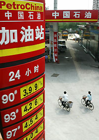 Cyclists pass under a board displaying oil prices at a PetroChina station in Beijing August 31, 2005. PetroChina Co. Ltd. is selling up to HK$21 billion ($2.7 billion) of shares at a discount of 5 to 7 percent, taking advantage of record oil prices that have sent its stock up 52 percent this year. 