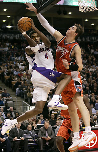 Toronto Raptors forward Chris Bosh (L) drives to the net on Charlotte Bobcats center Primoz Brezec during the first half of their NBA game in Toronto, Canada January 11, 2006.[Reuters]