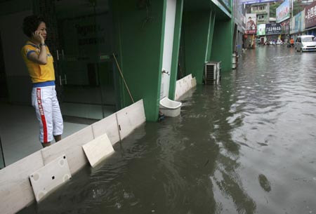 A woman makes a phone call near a flooded street in southwest China's Chongqing municipality July 17, 2007. Heavy rains will continue in most parts of the country in the next ten days, the China Meteorological Administration forecast on July 15, Xinhua News Agency said